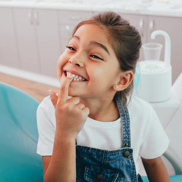 little girl pointing to teeth in dental office